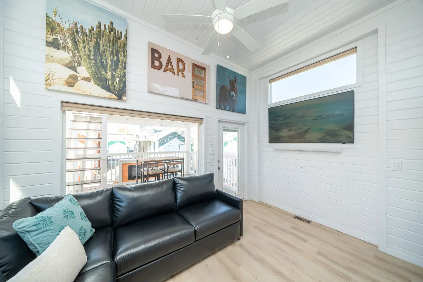 A living room with a black couch and a ceiling fan.