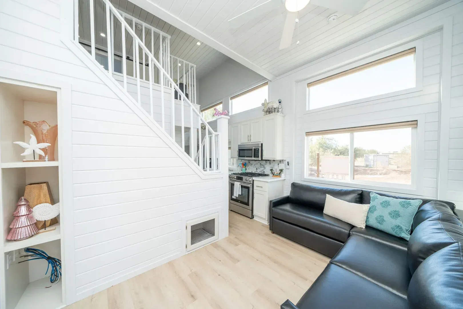 A living room with a black couch and stairs leading up to the second floor.