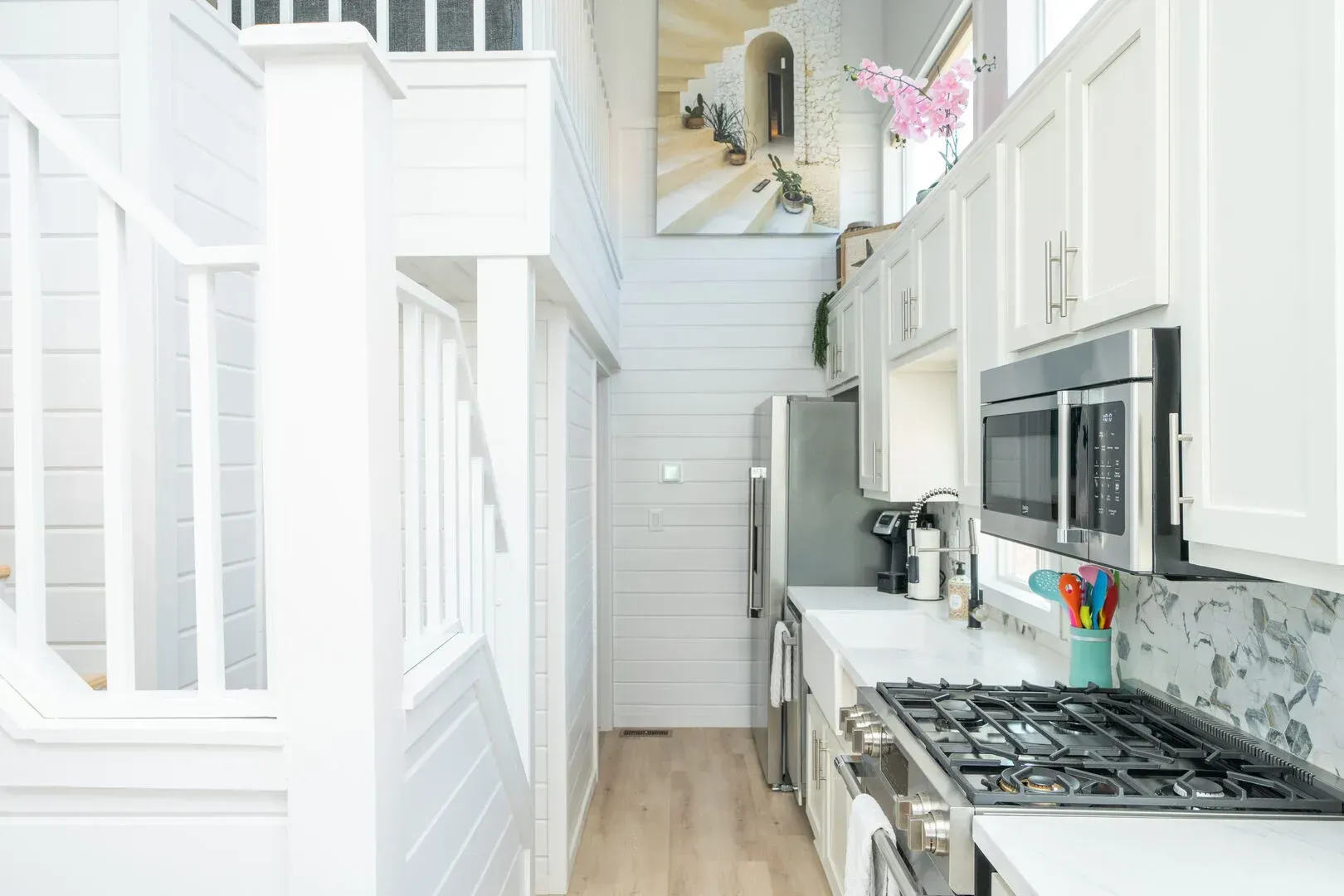 A kitchen with white cabinets , a stove , a refrigerator , and a microwave.