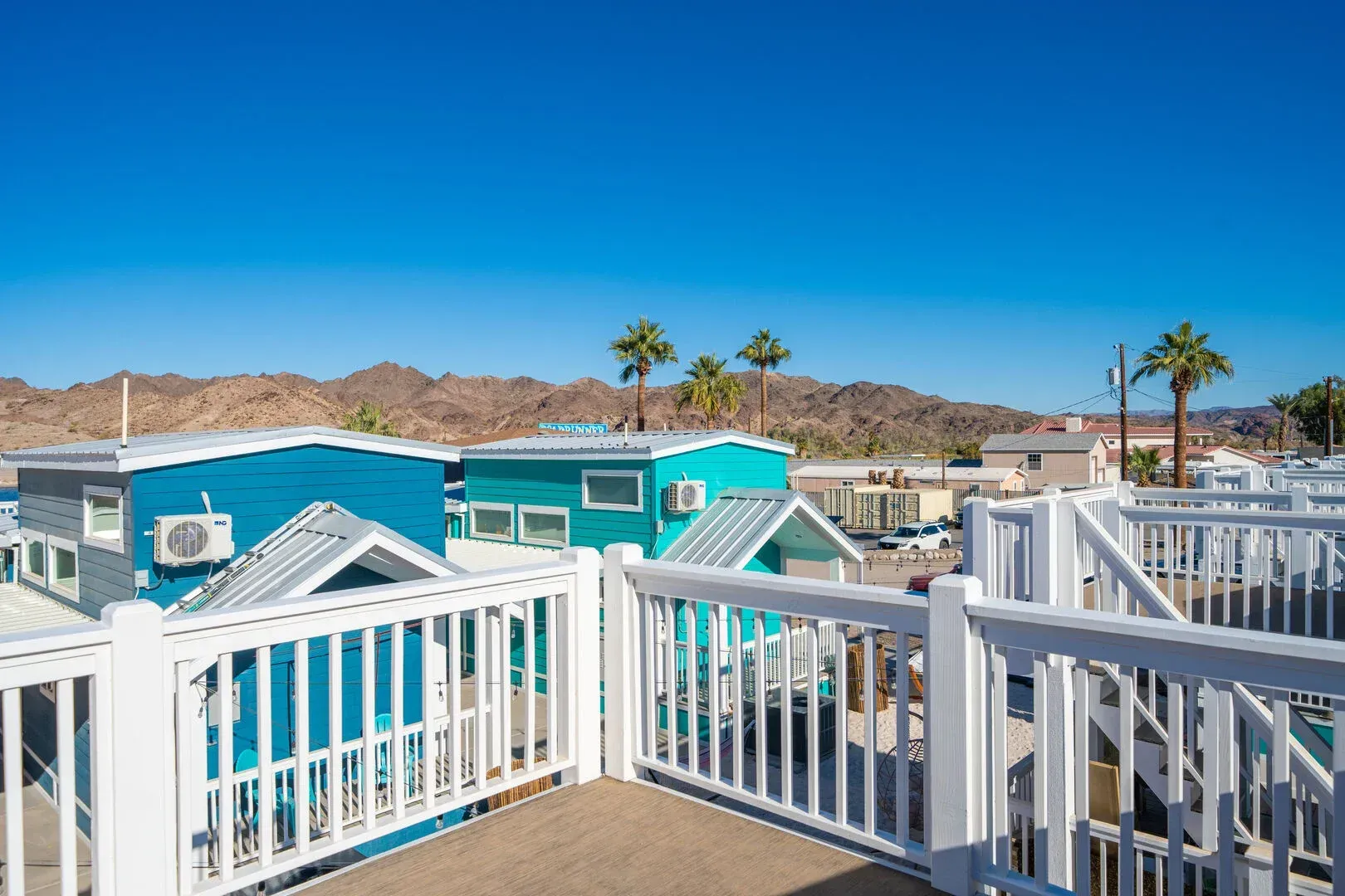 A balcony with a view of a row of houses and palm trees.