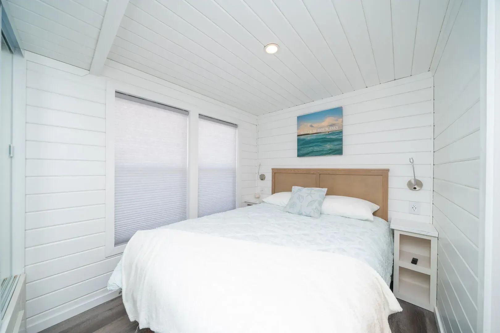 A bedroom with a large bed and a painting on the wall.