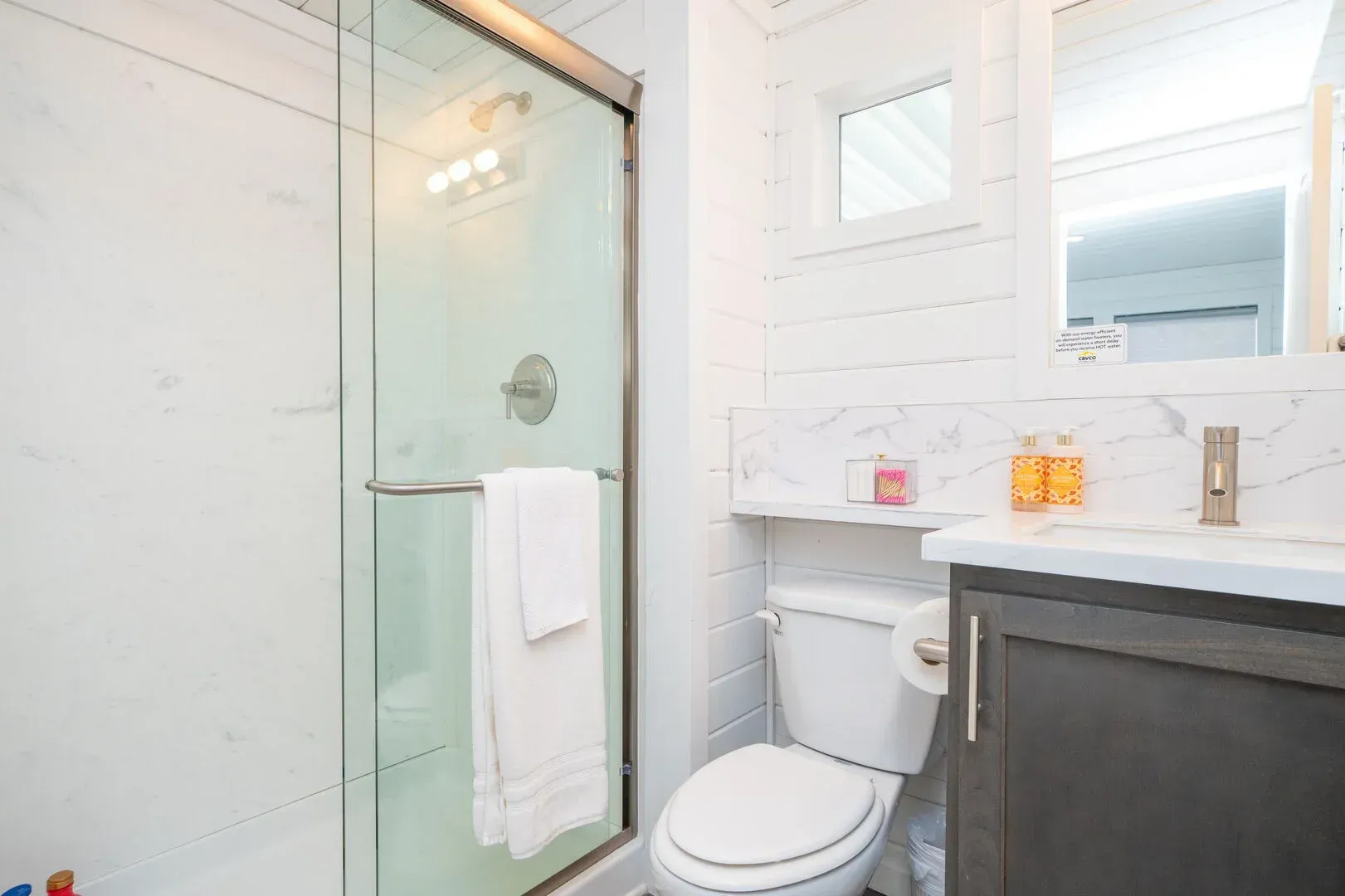 A bathroom with a toilet , sink , mirror and shower.