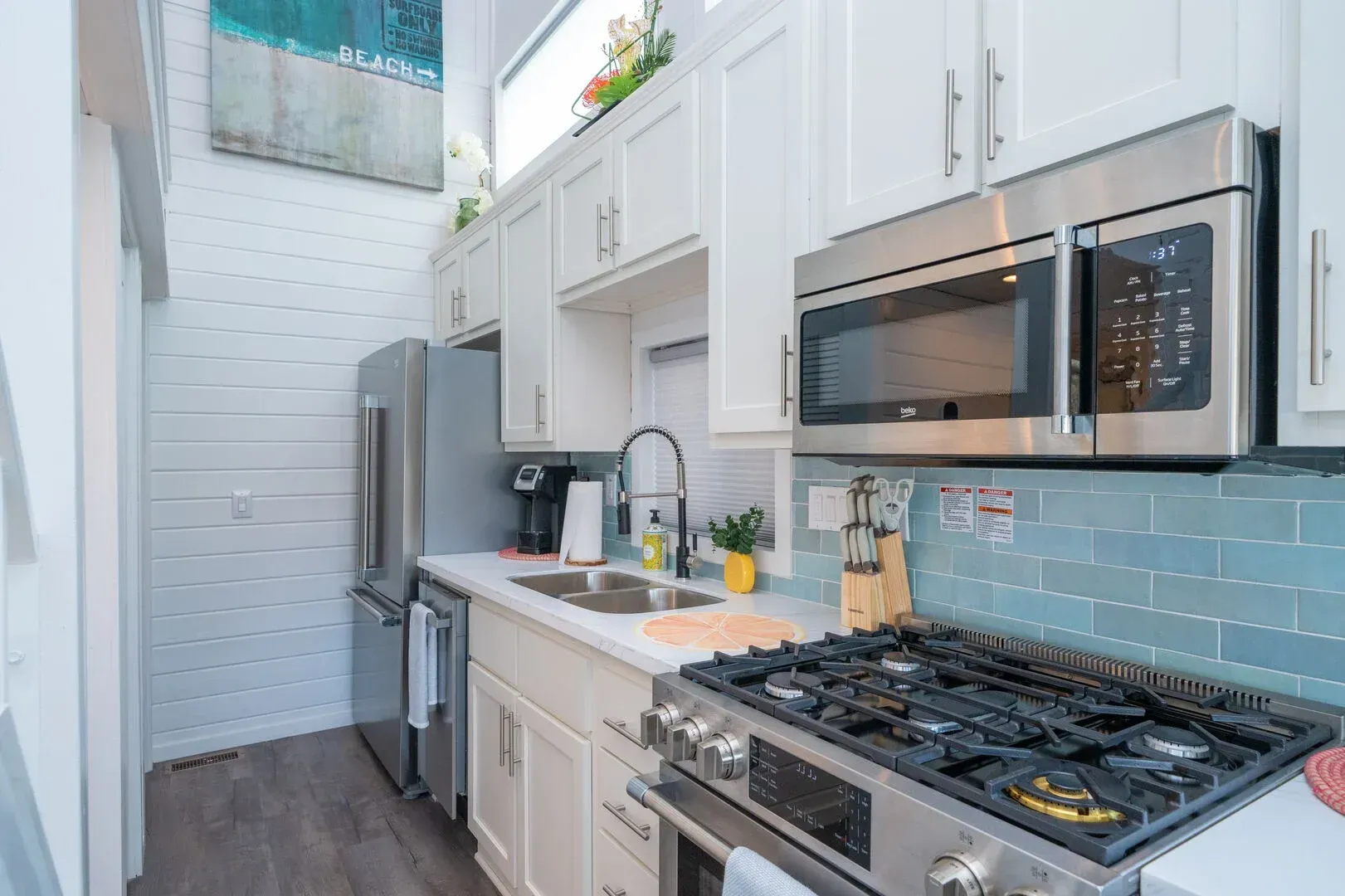 A kitchen with a stove , microwave , refrigerator and sink.