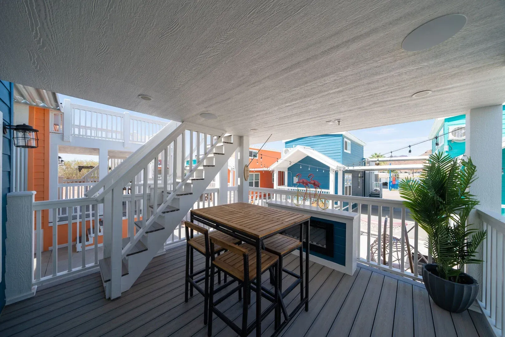 There is a table and chairs on the deck of a house.