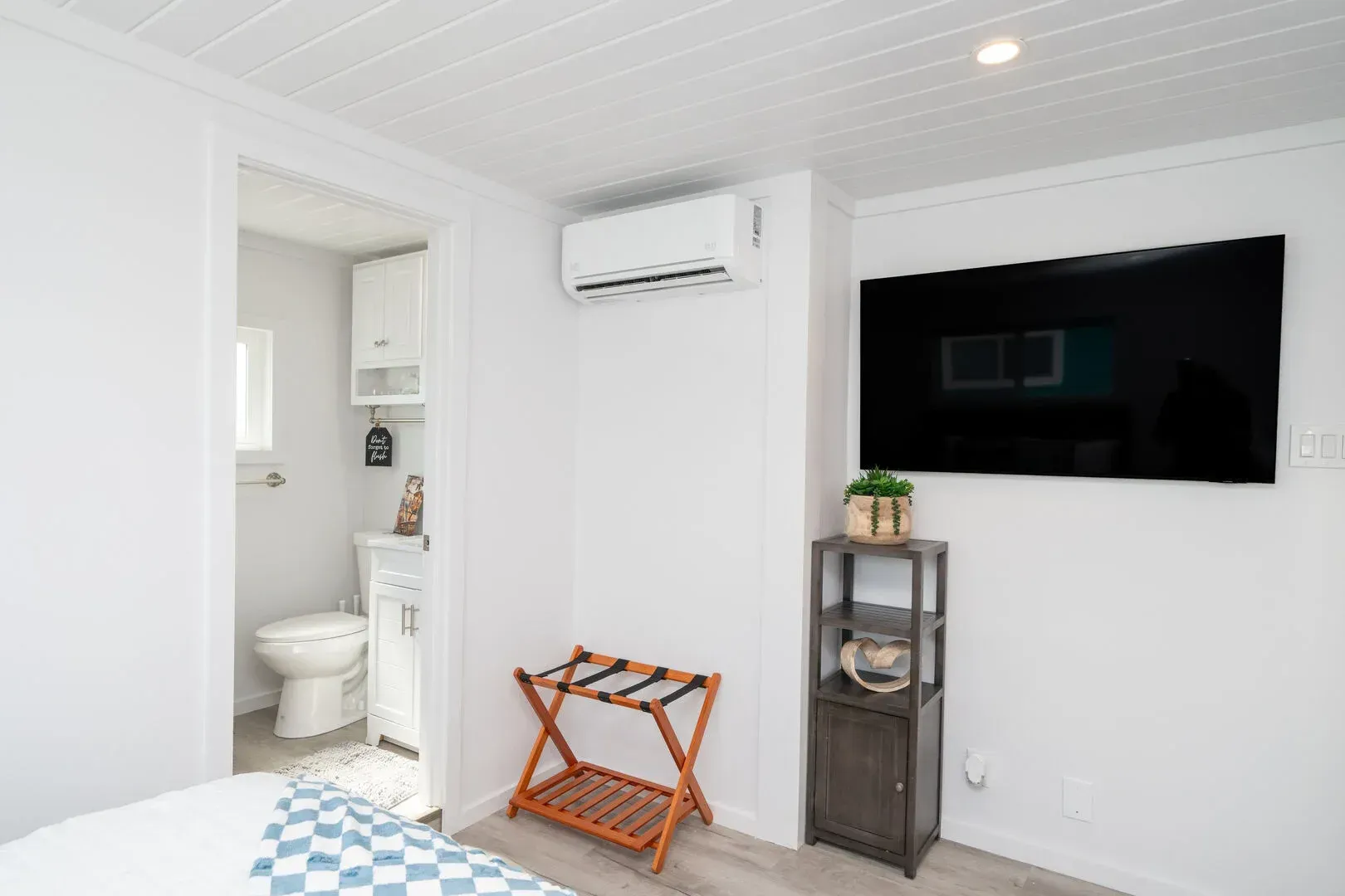 A bedroom with a bed , television , and toilet.