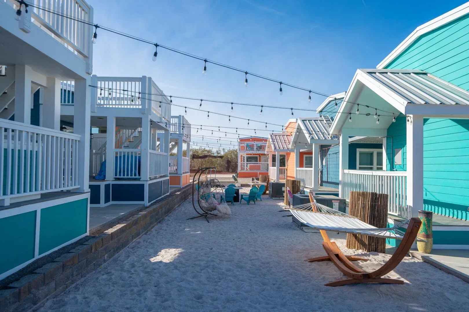 A row of small houses on a beach with a table and chairs.
