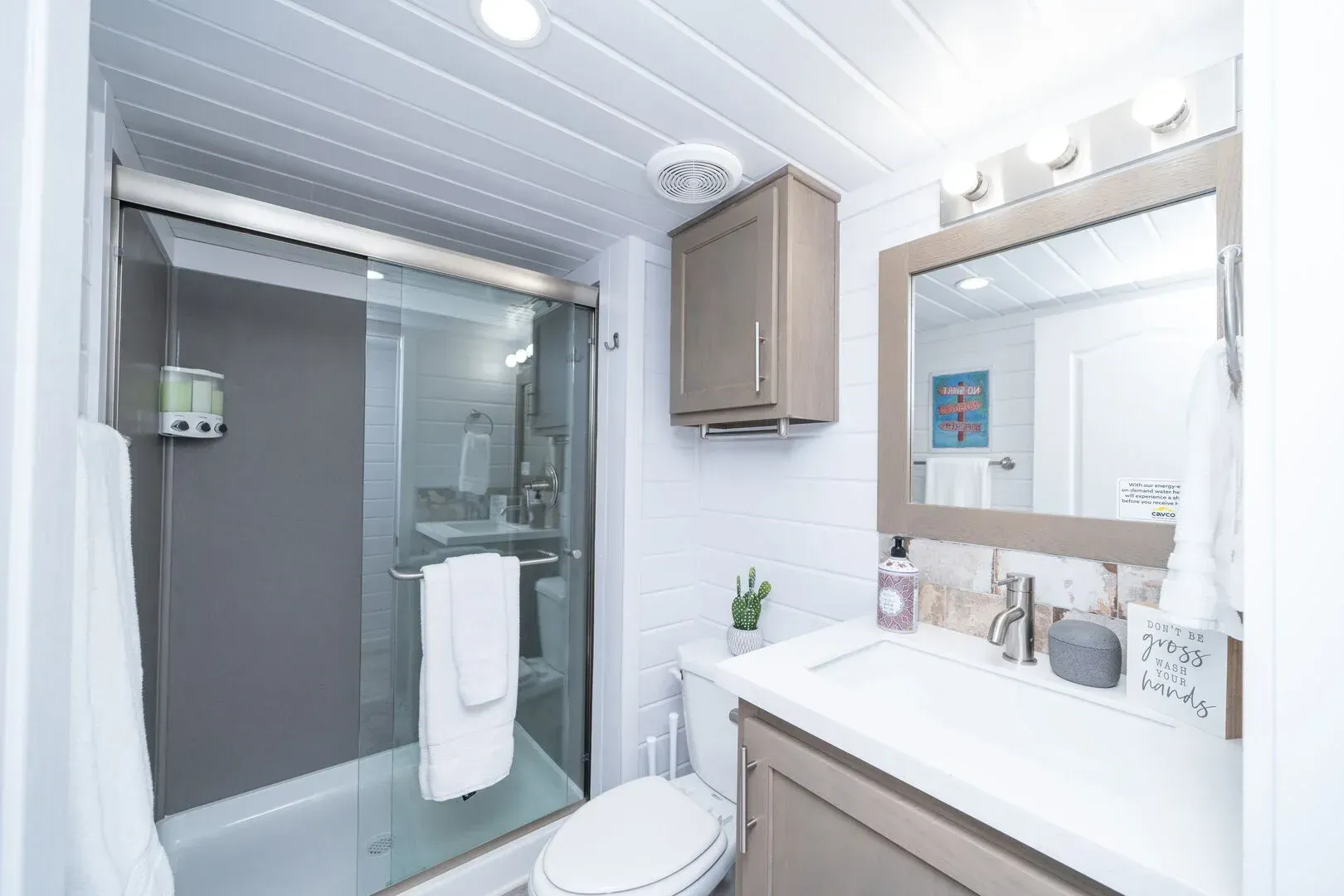 A bathroom with a toilet , sink , mirror and shower.