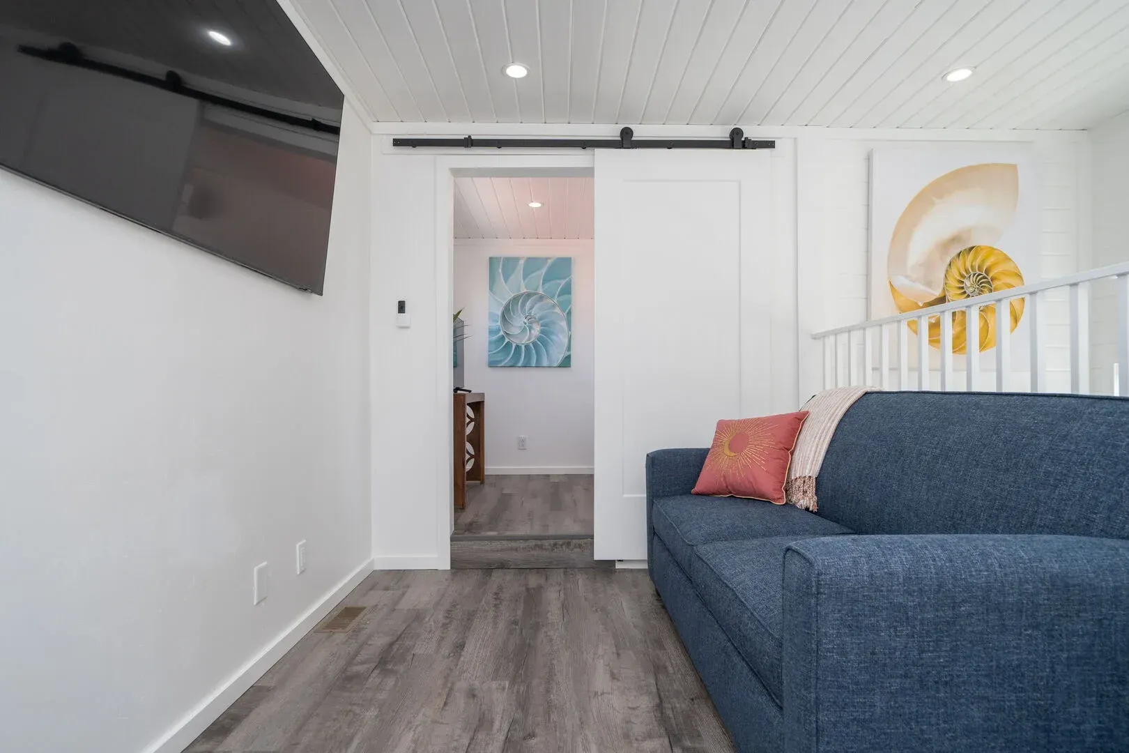 A living room with a blue couch and a sliding barn door.