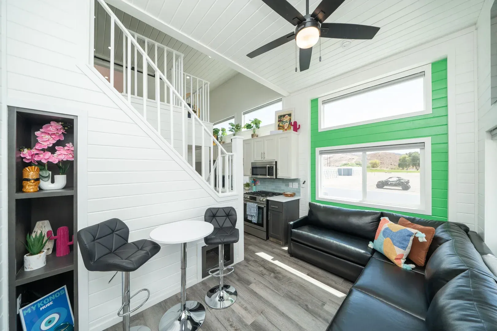 A living room with a couch , table , chairs and a ceiling fan.