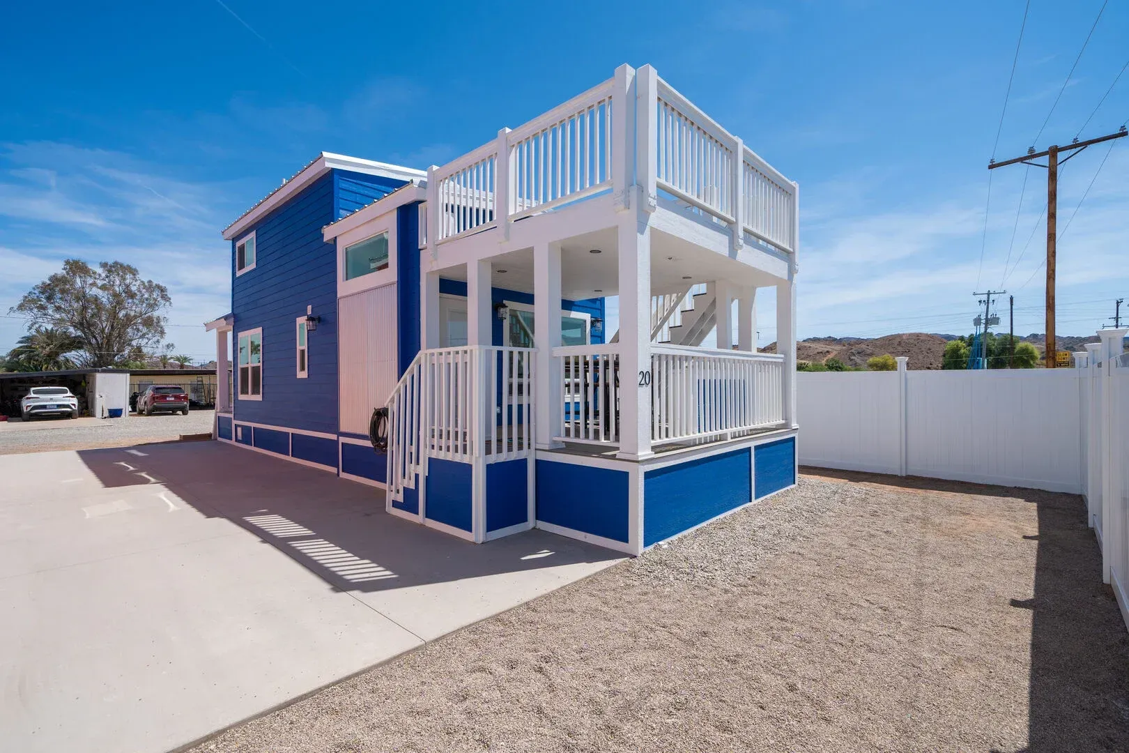 A blue and white house with a white fence in front of it.