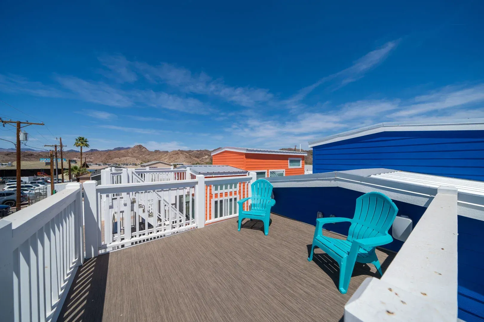 A balcony with blue chairs and a white railing