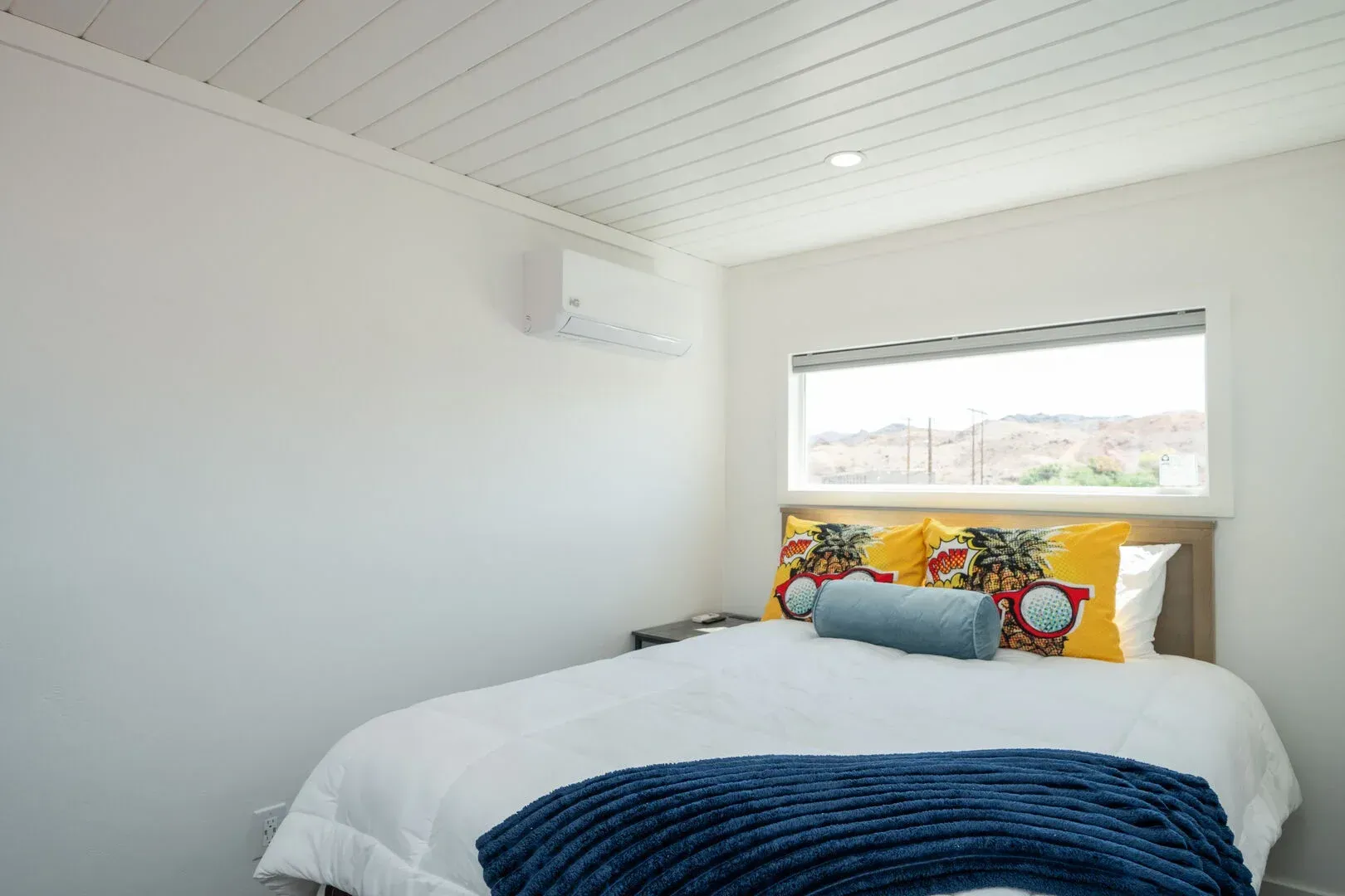 A bedroom with a bed , window and air conditioner.