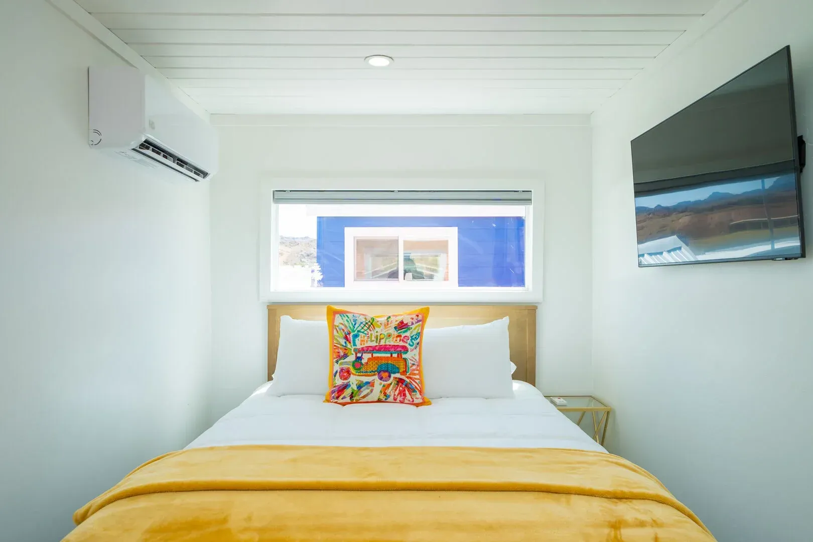 A bedroom with a bed , television and air conditioner.