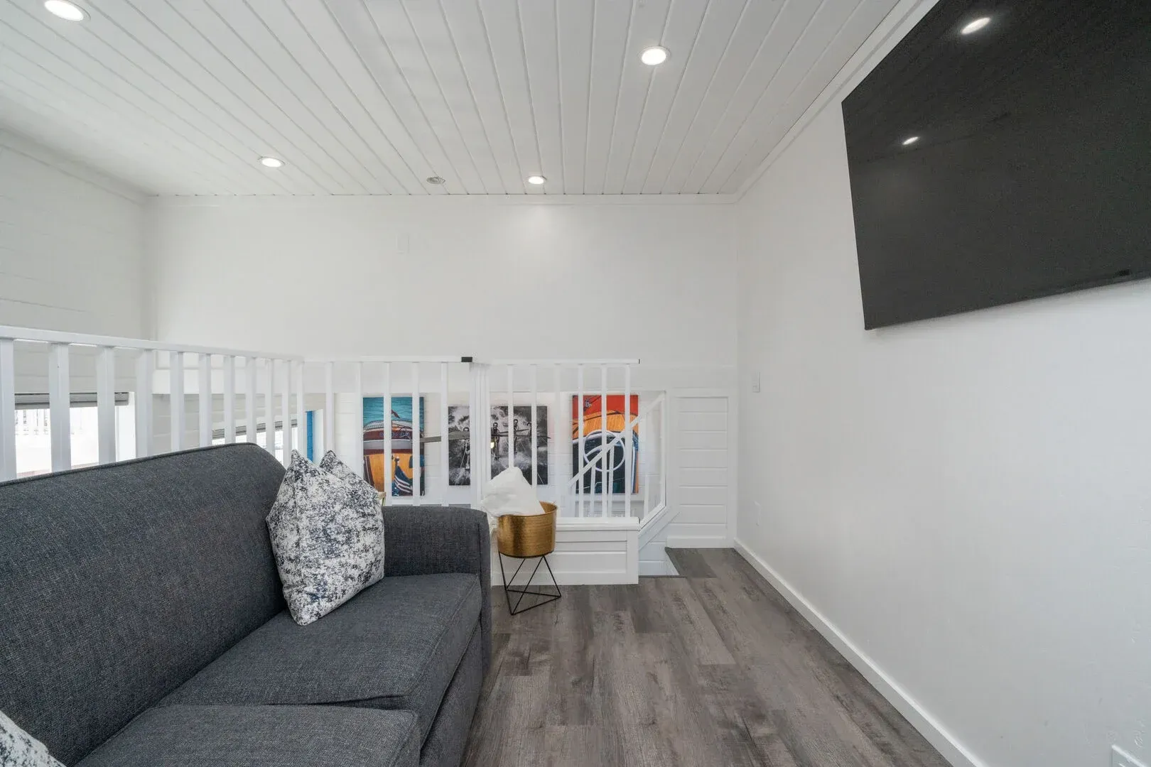 A living room with a couch and a flat screen tv on the wall.