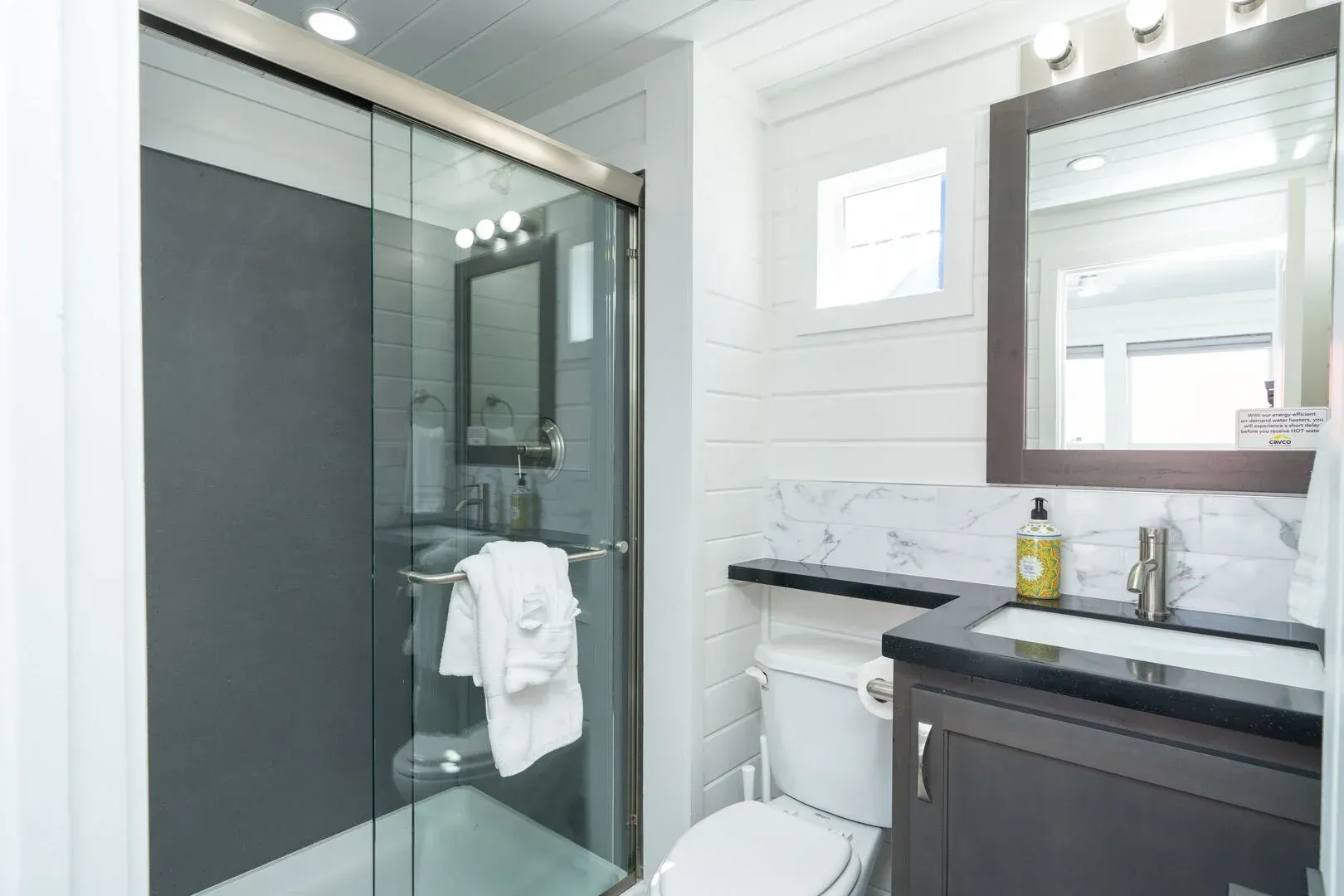 A bathroom with a toilet , sink , mirror and shower.