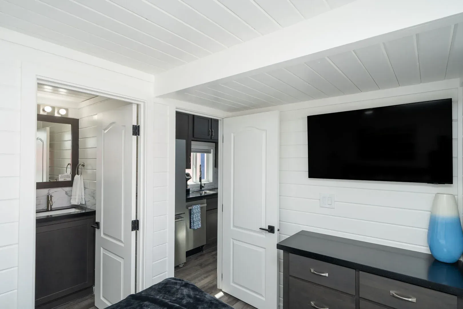 A bedroom with a bed , dresser , television and bathroom.