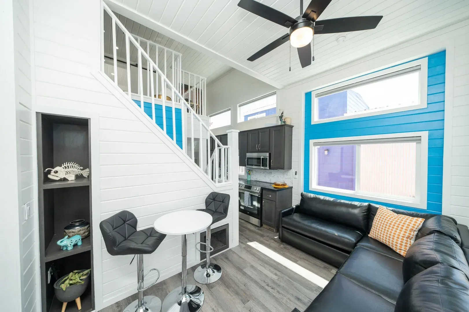 A living room with a couch , table , chairs and a ceiling fan.