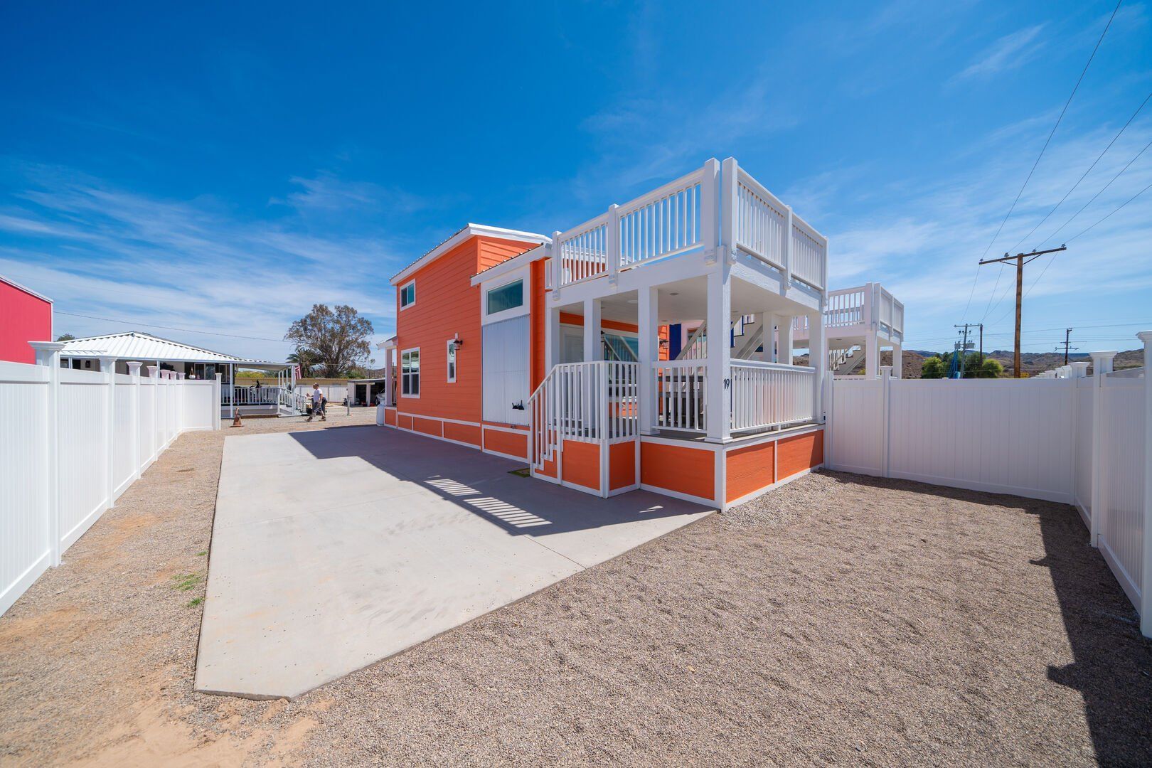 A large orange and white house with a white fence in front of it.