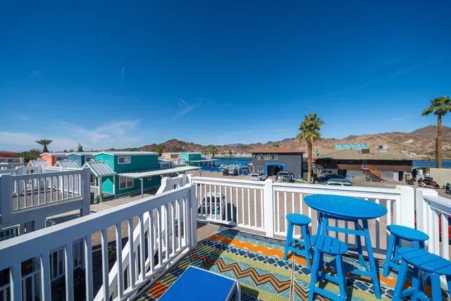 A balcony with blue tables and stools and a view of a city.