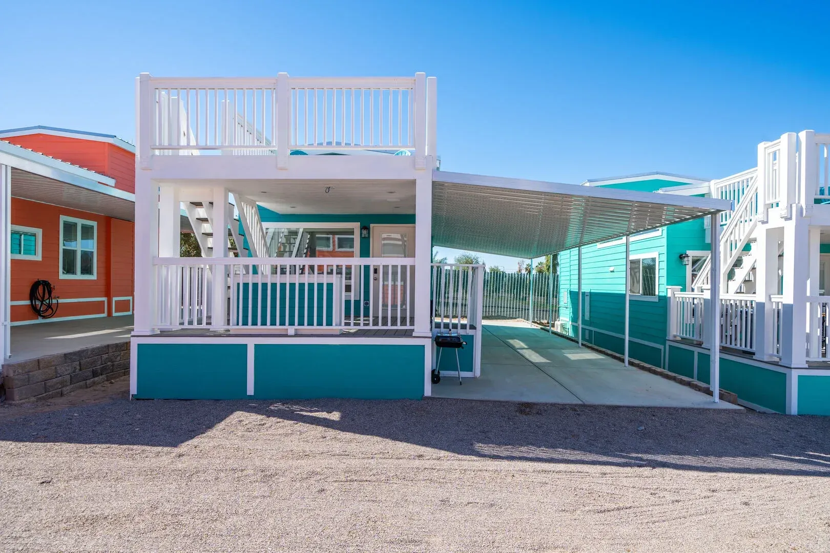 A blue and white mobile home with a balcony and a driveway.