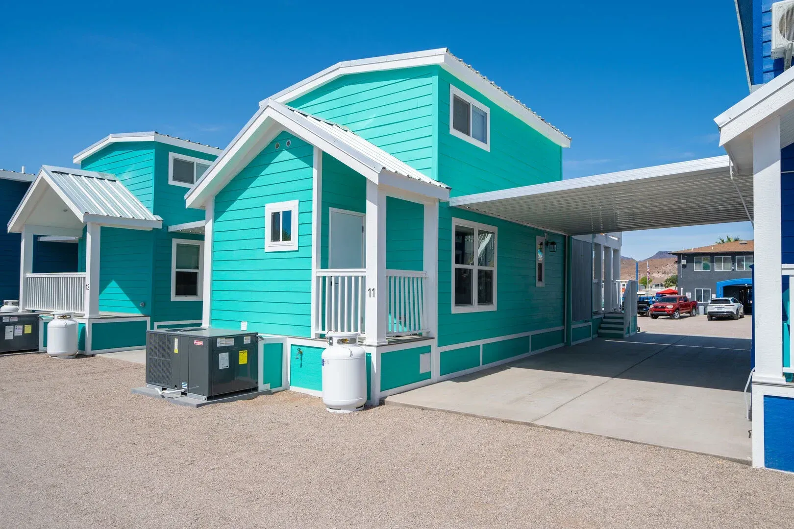 A green and white house with a carport in front of it.