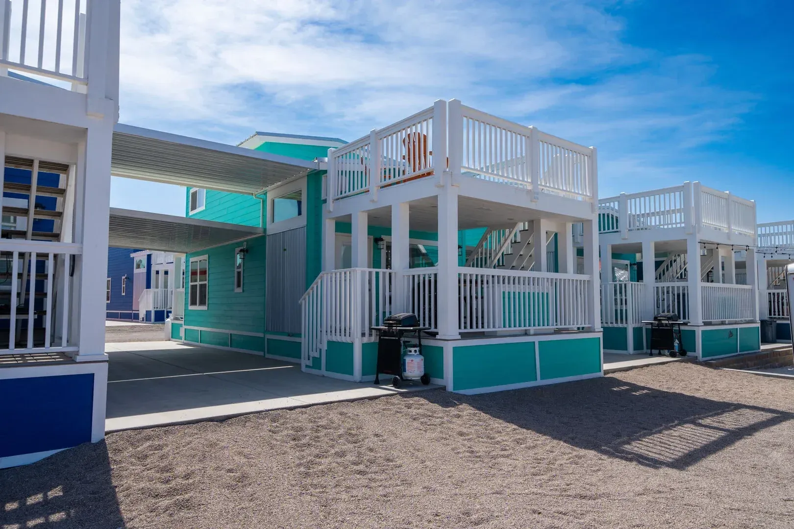 A row of teal and white mobile homes with balconies.