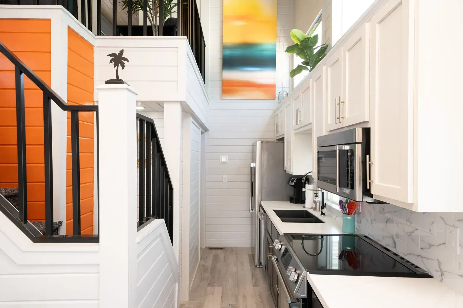 A kitchen with white cabinets and stainless steel appliances and a staircase leading to the second floor.