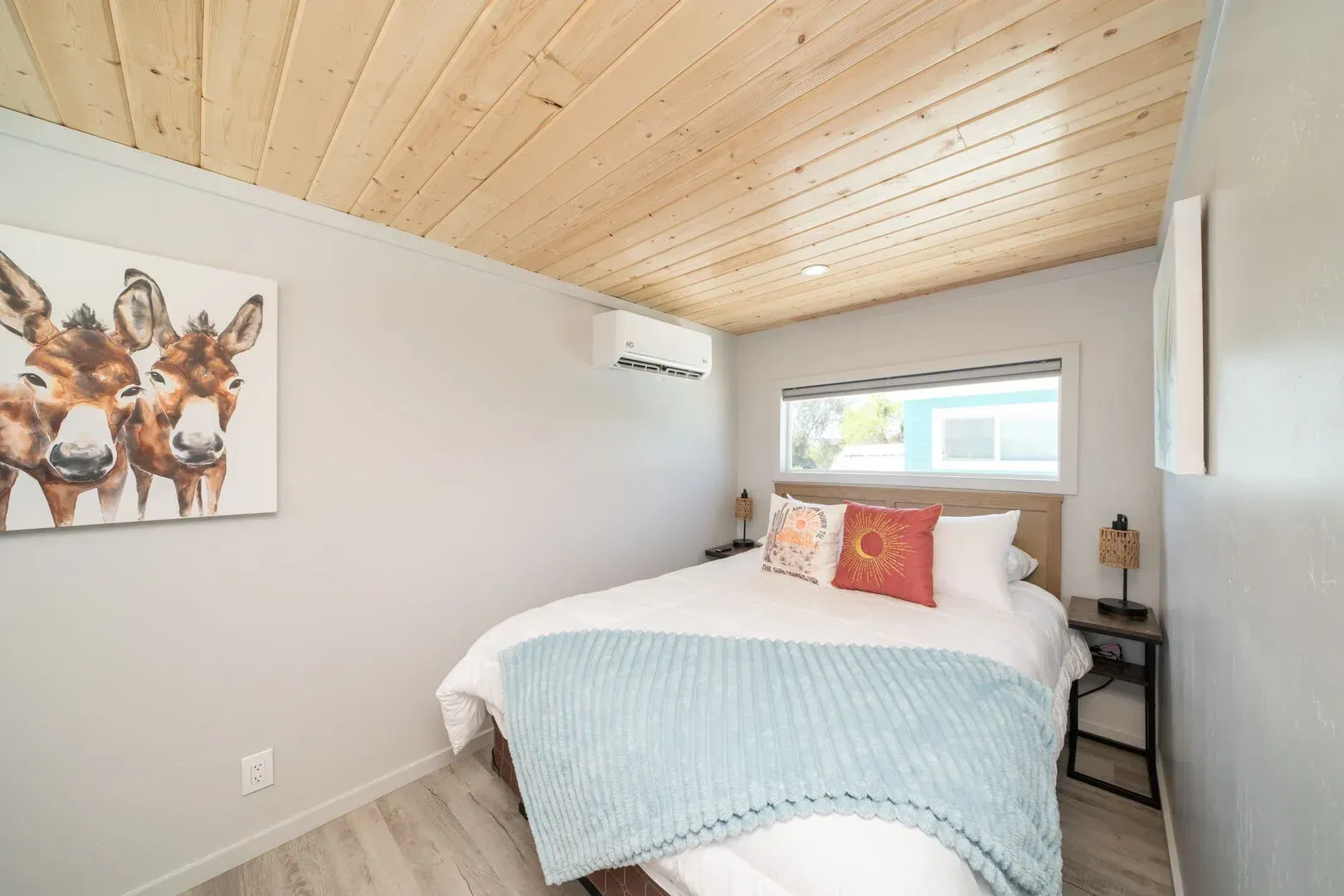 A bedroom with a bed and a painting of donkeys on the wall.