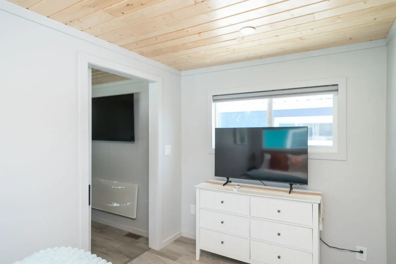 A bedroom with a dresser and a flat screen tv