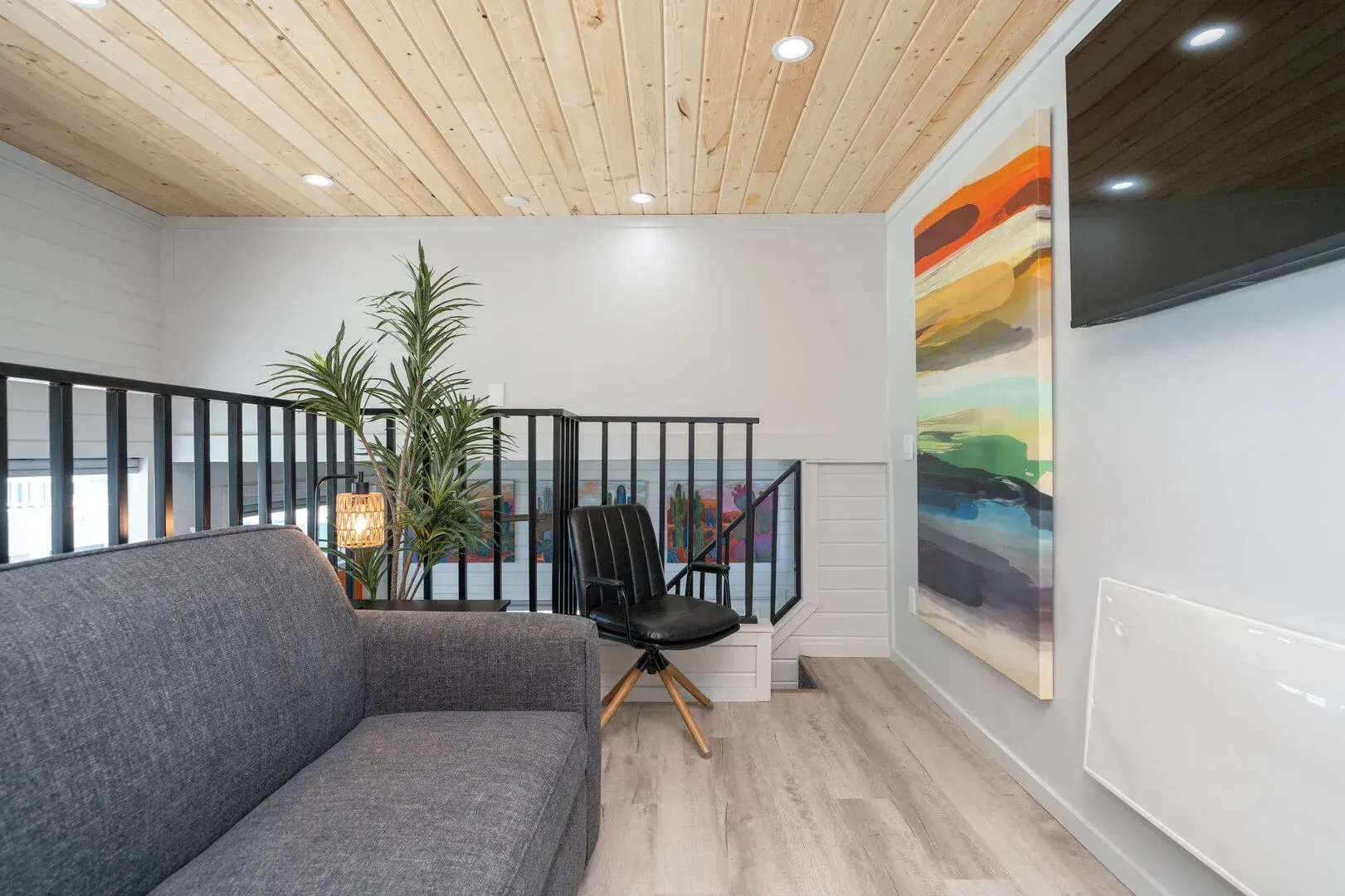 A living room with a couch and chair and a painting on the wall.