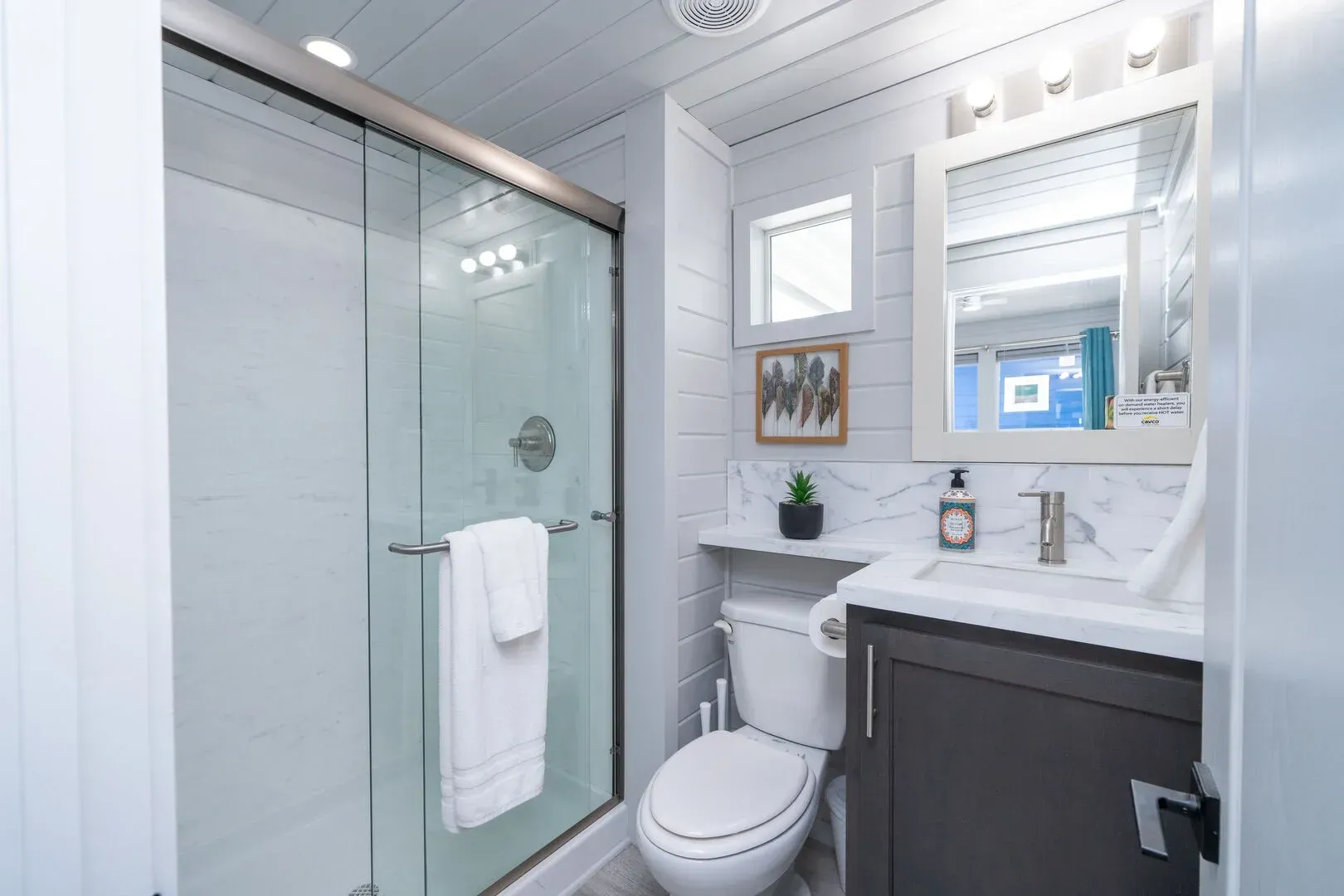 A bathroom with a toilet , sink and shower.