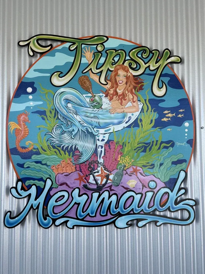 A painting of a mermaid in a glass with the words ' tipsy mermaid ' on it