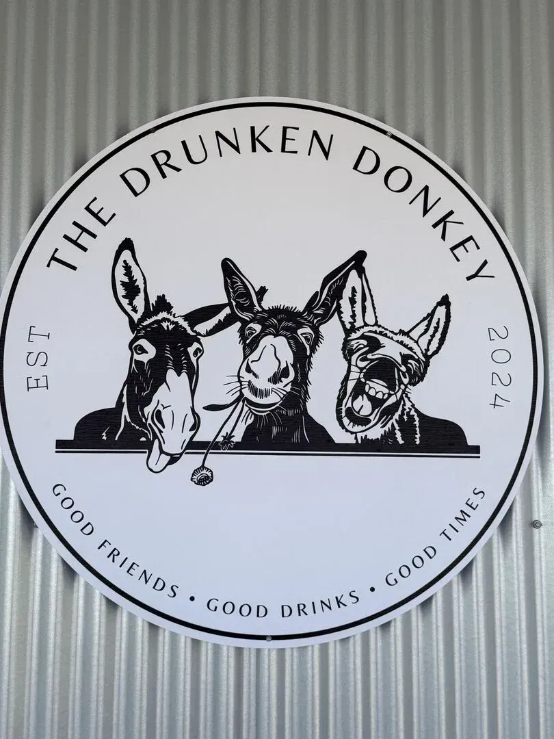 A sign for the drunken donkey with three donkeys on it