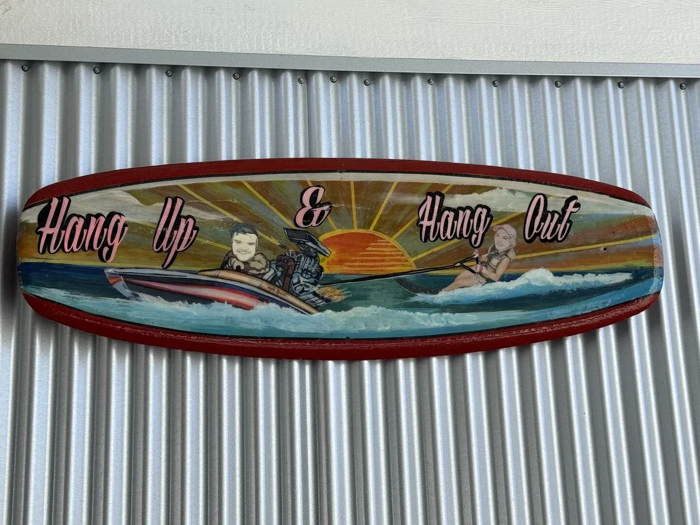 A surfboard with a picture of people on it is hanging on a wall.