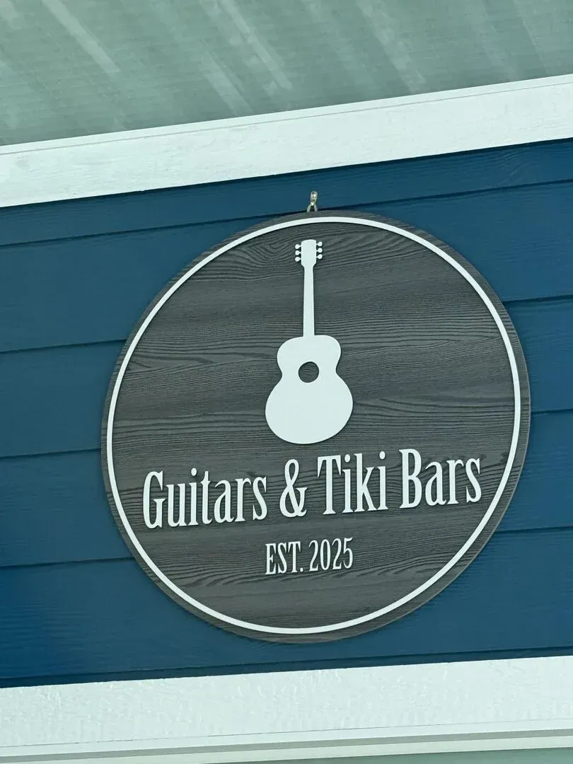 A sign that says guitars and tiki bars on it
