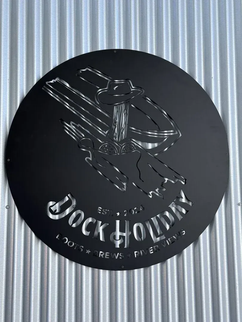 A black sign on a metal wall that says dock holiday