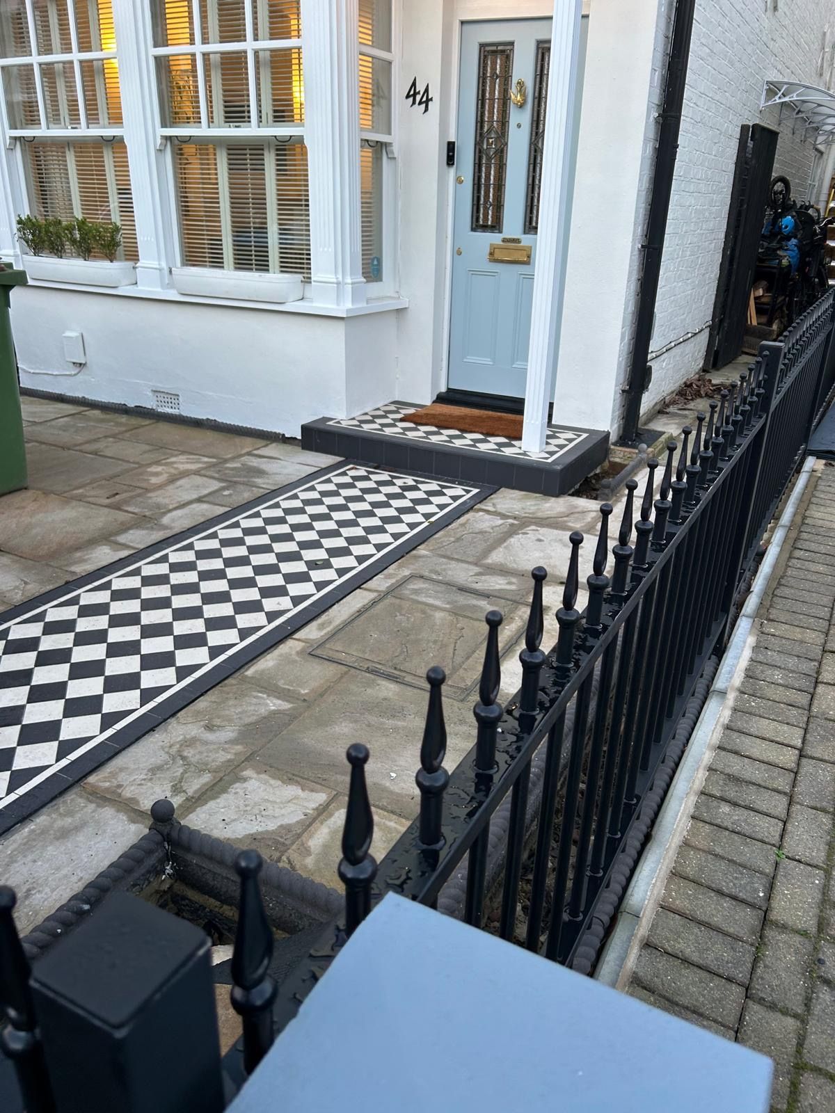 A black and white tiled walkway leading to the front door of a house.