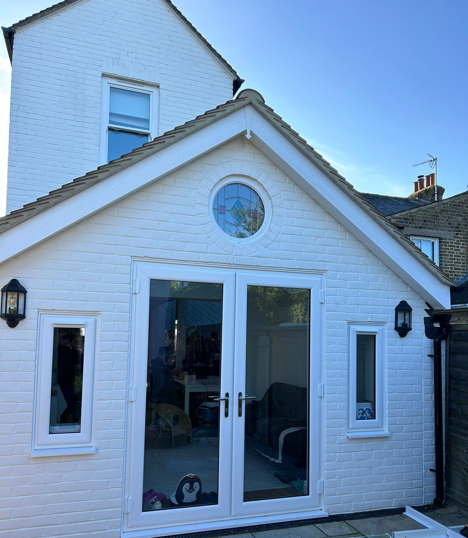 A white brick house with a round window on the roof