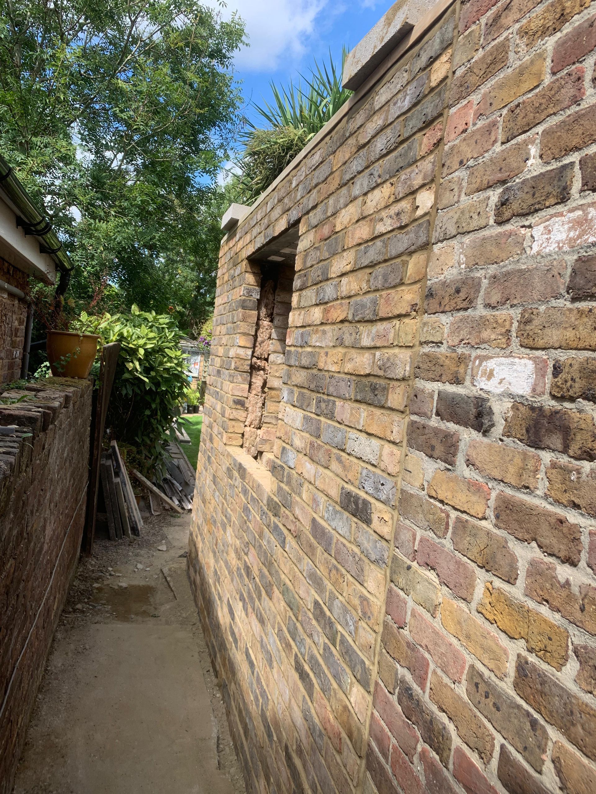 A brick wall with a window in the middle of it.