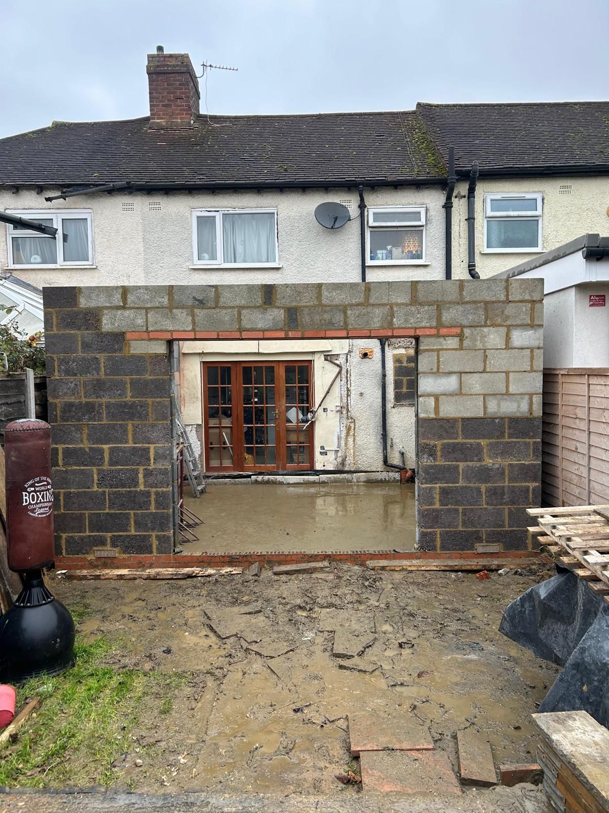 A brick wall is being built around a house.