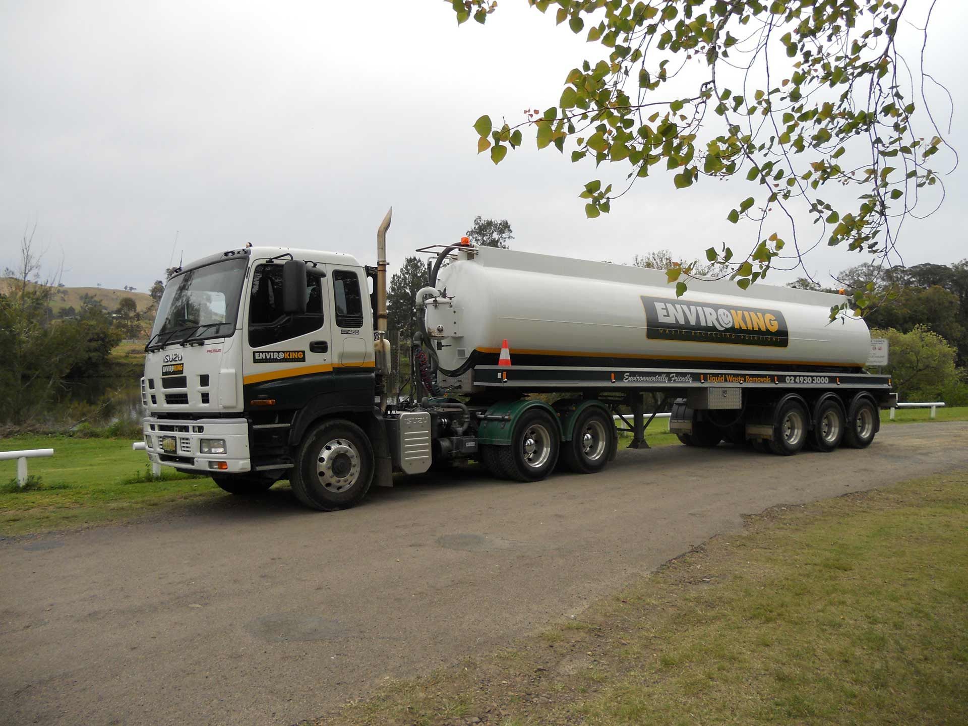Tanker truck parked on a gravel road, with a silver tank labeled 