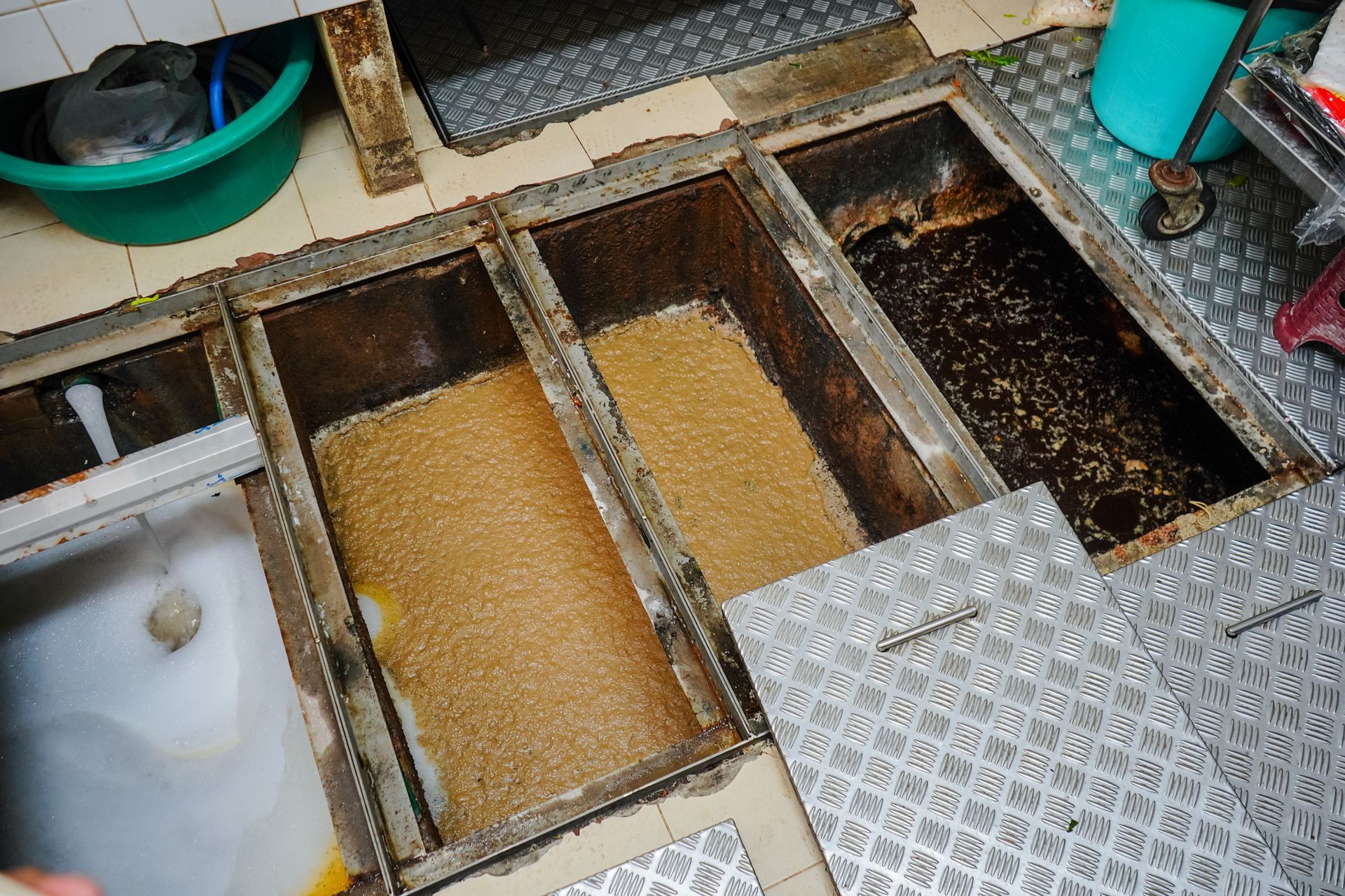 Open metal grease traps filled with brown liquid and debris.