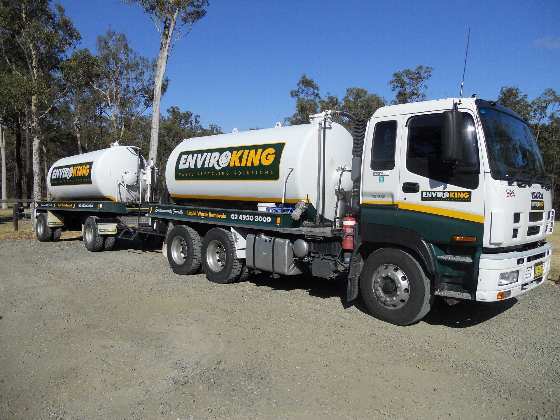White truck and trailer with EnviroKing logo, parked outdoors on gravel.