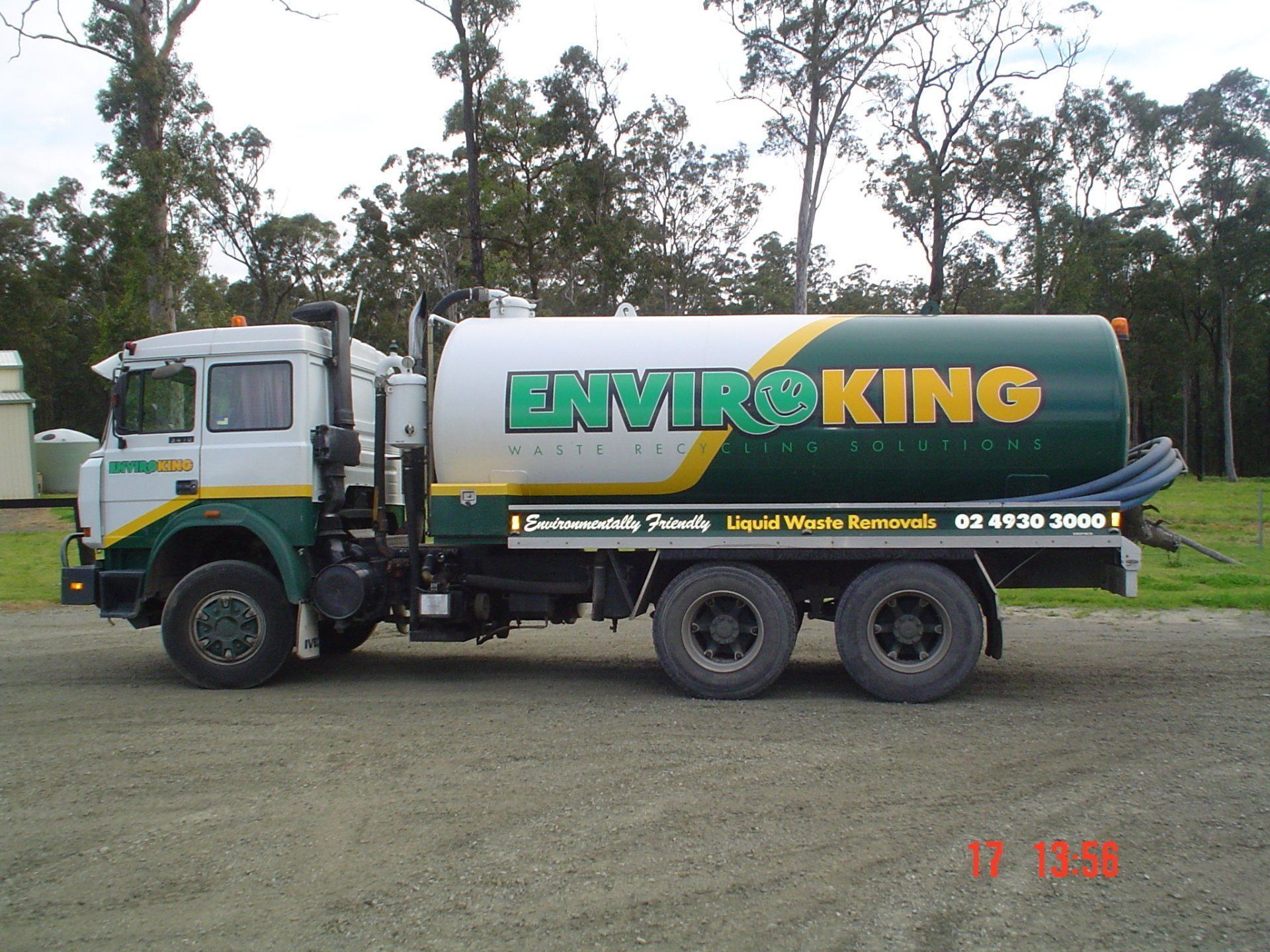 White and green Enviro King truck for liquid waste removal parked outdoors.