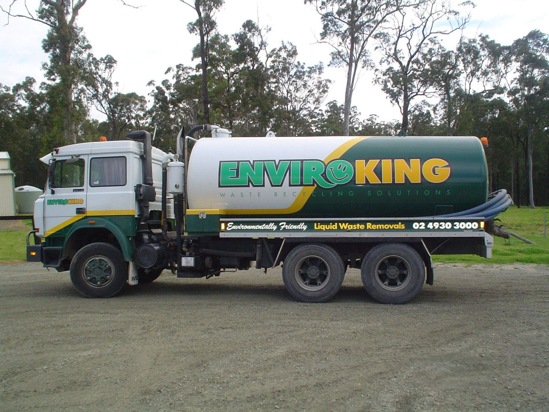 White and green Enviroking septic truck parked outdoors on gravel.