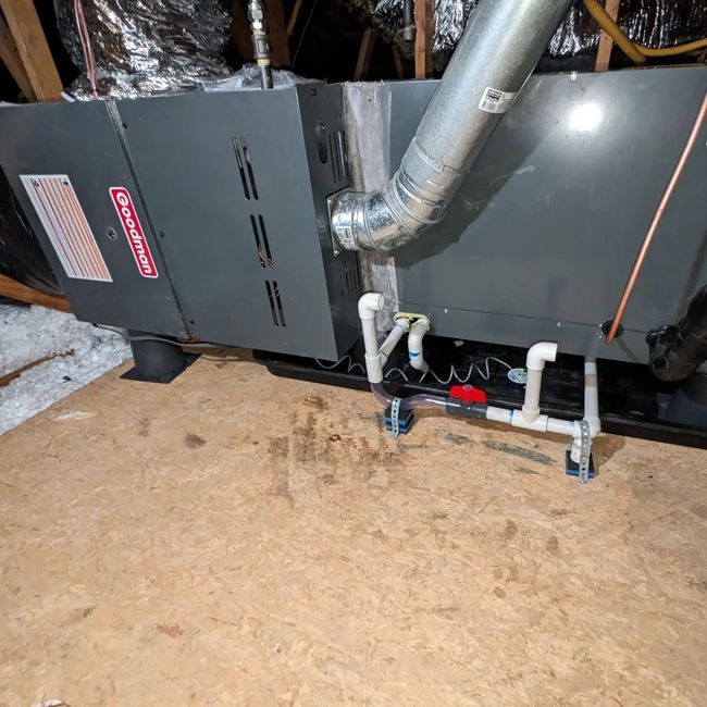 Goodman HVAC unit in an attic, with ductwork and plumbing visible.