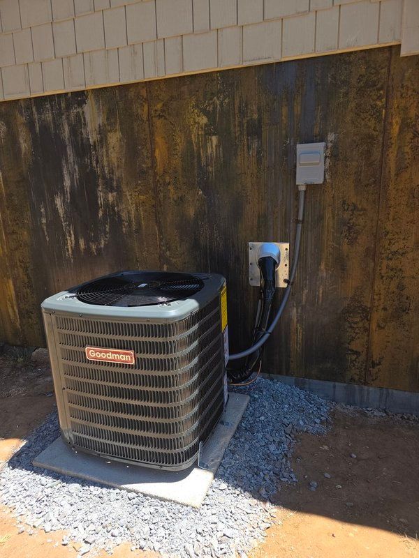 Air conditioning unit on a concrete pad with electrical connections against a weathered wall.