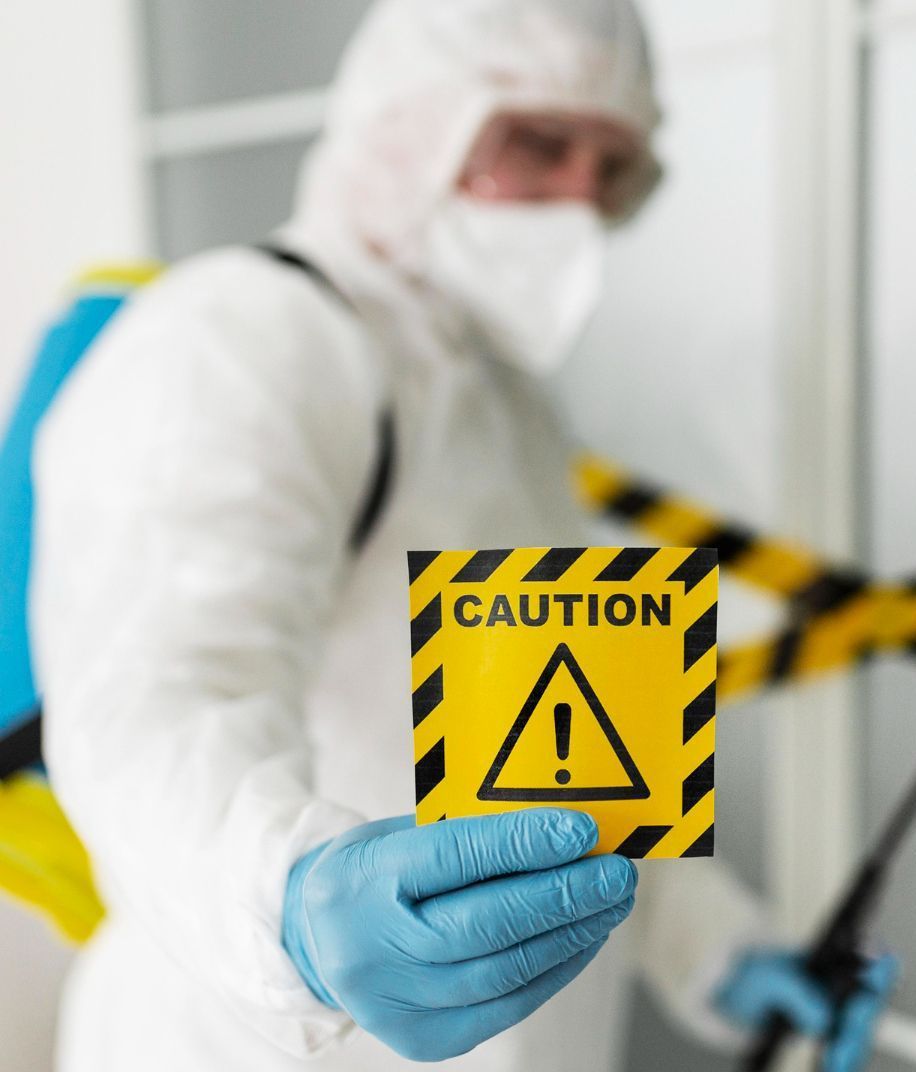 A man in a protective suit is holding a caution sign