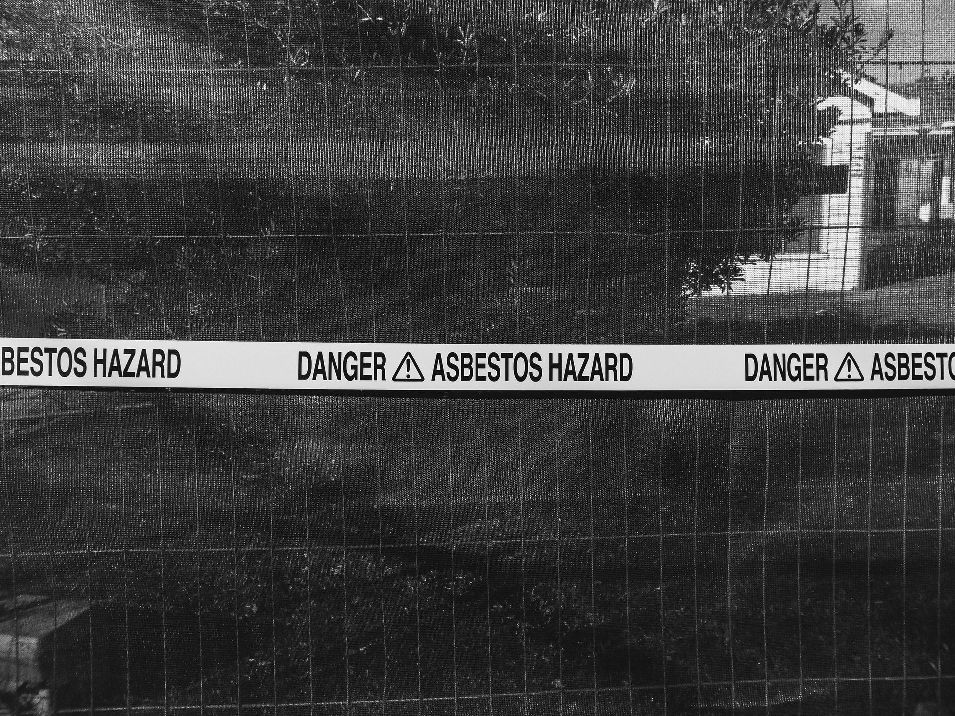 A black and white photo shows a chain-link fence with a