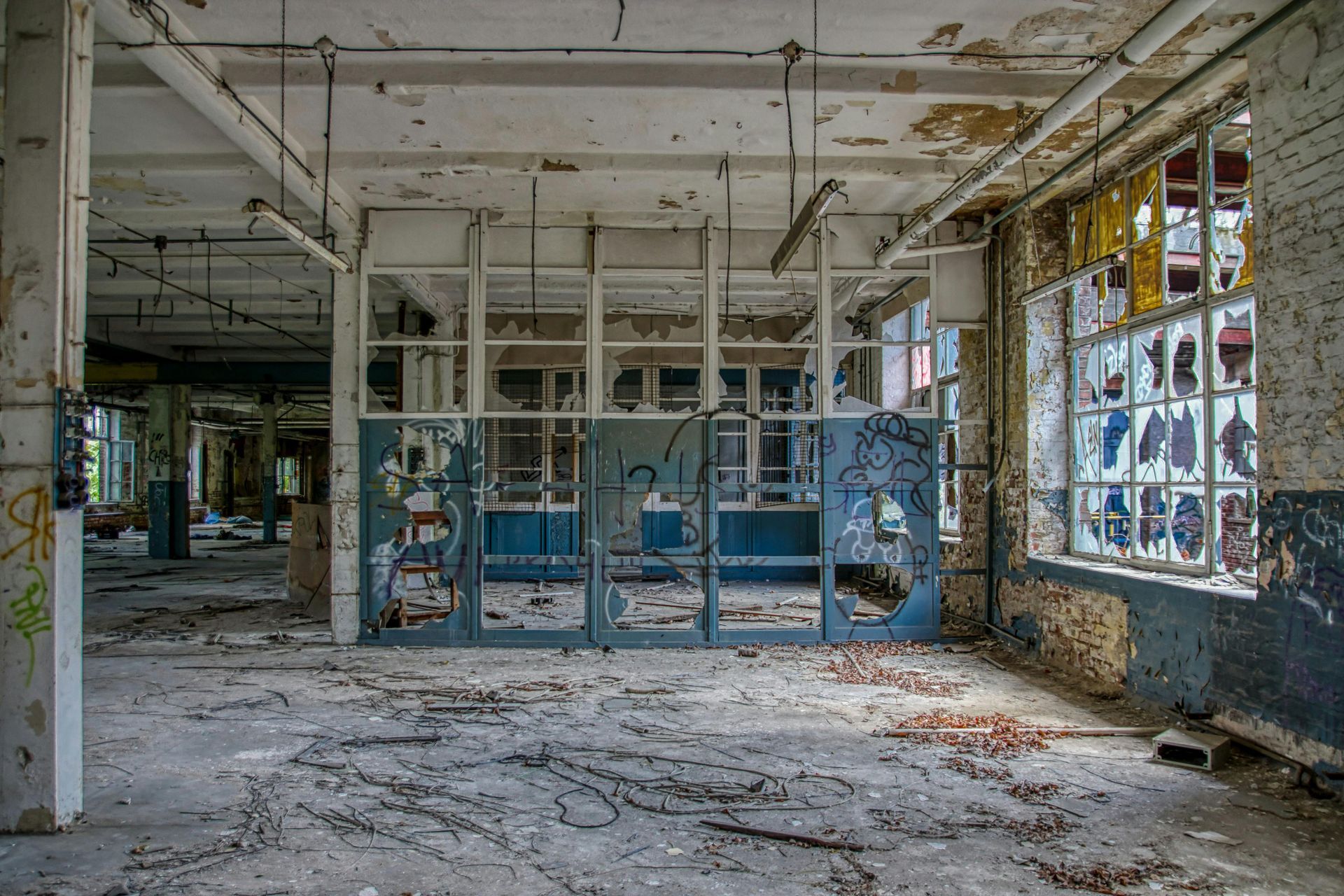 Interior of an abandoned industrial building. The room is dusty, with crumbling walls and broken windows.